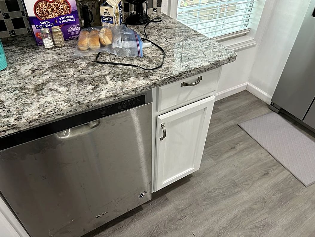 Kitchen with granite countertop, white cabinets and a stainless dishwasher
